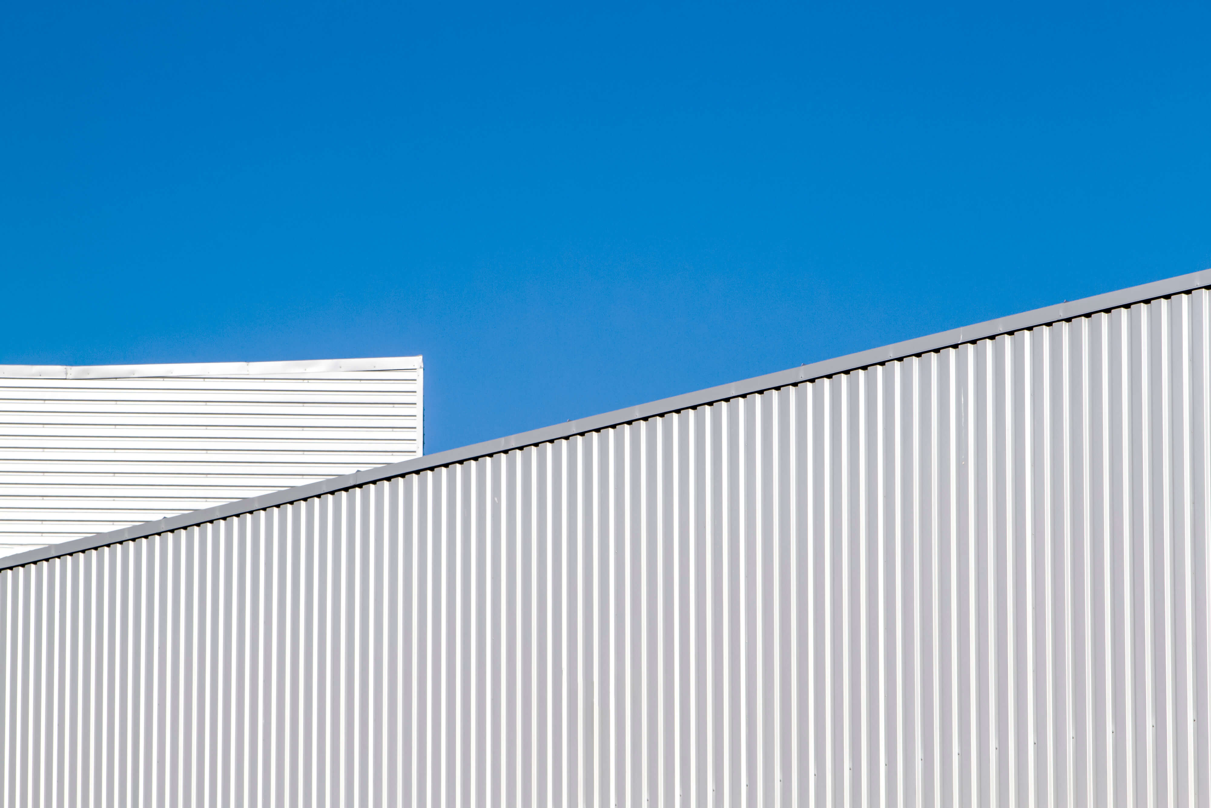 Corrugated sheet metal wall and roof against blue sky. Modern